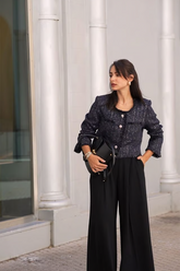 a lady wears a navy blue tweed jacket with a round neck design and  loose fit black pants